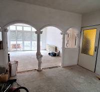 Das Innere eines Einfamilienhauses mit gewölbten Bögen und Glastüren. Reparaturen sind im Gange.