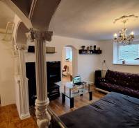 Wohnzimmer in einem Einfamilienhaus mit Sofa, Glastisch und Säulen.