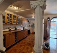 Innenraum eines Einfamilienhauses mit Holzküchenzeile, Säulen und Boden mit Holzdekor.