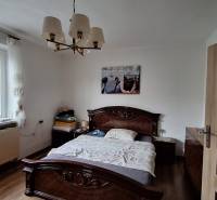 Schlafzimmer in einem Einfamilienhaus mit Bett, Kronleuchter und Boden in Holzoptik.