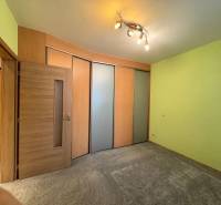 Ein Zimmer in einer 3-Zimmer-Wohnung mit Schiebetüren, grünen Wänden und Spotbeleuchtung.