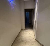 Flur mit Holzboden, Beleuchtung und weißen Wänden in einer 3-Zimmer-Wohnung.