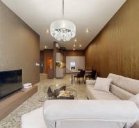 Wohnzimmer in einer 3-Zimmer-Wohnung mit einem bequemen Sofa, einem Kronleuchter und einem Fernseher.