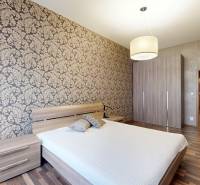 Schlafzimmer in einer 3-Zimmer-Wohnung mit gemusterten Tapeten und Holzboden.