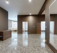 Ein geräumiger Flur mit Fliesen, einem Spiegel, zwei Stühlen und Blick ins Wohnzimmer.