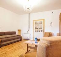 Wohnzimmer in einem Einfamilienhaus mit Holzboden, Sofa und Sesseln.