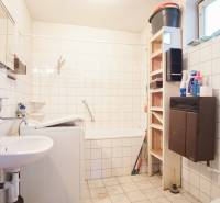 Badezimmer in einem Einfamilienhaus mit Badewanne, Waschbecken, Waschmaschine und Regalspeicher.