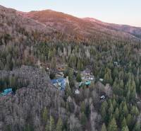 Luftaufnahme von Hütten im Wald in der Region Krpáčovo, umgeben von Bergen und dichtem Baumbestand.