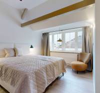 Ein Schlafzimmer mit hellem Boden in Holzoptik, großem Fenster und bequemem Sessel.