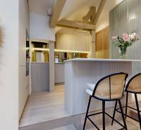 Innenraum einer 4-Zimmer-Wohnung mit Barhockern, dekorativer Wand und Blumen in einer Vase.