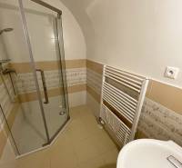 Badezimmer in einem Gebäude mit Keramikfliesen, Duschkabine und Handtuchheizkörper.