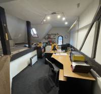 Ein Büro in einem Gebäude mit Holzbalken, ausgestattet mit Tischen und Büromaterialien.