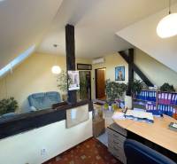 Ein Büro in einem Gebäude mit einem Holzboden, Regalen für Dokumente und einer Sitzecke.