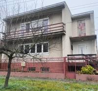 Ein Einfamilienhaus in Dlhá nad Váhom mit Betonfassade, Balkon und Vorgarten.