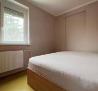 Schlafzimmer in einem Einfamilienhaus mit einfachem Bett, Fenster und Heizkörper.