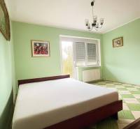 Ein Schlafzimmer in einem Einfamilienhaus mit einem Bett, pastellfarbenen Wänden und einem Schachbrettboden.