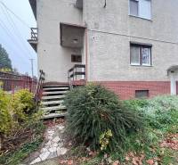Ein Einfamilienhaus in Dlhá nad Váhom mit einem Ziegelsockel, einer Treppe und einem gepflegten Garten.