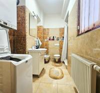 Badezimmer mit Waschmaschine, Waschbecken, Toilette und hellem Keramikfliesenboden in einer 3-Zimmer-Wohnung.