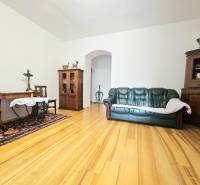 Wohnzimmer in einer 3-Zimmer-Wohnung mit Holzboden, Sofa und Holzmöbeln.