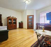 Wohnzimmer in einer 3-Zimmer-Wohnung mit Holzboden und Möbeln aus dunklem Holz.