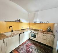 Küche in einer 3-Zimmer-Wohnung mit cremefarbenen Schränken, gelben Fliesen und gemustertem Teppich.