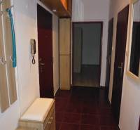 Der Flur einer 2-Zimmer-Wohnung mit dunklen Fliesen und Holzmöbeldekor.