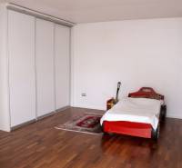 Kinderzimmer in einem Einfamilienhaus mit einem Bett in Form eines Autos und einem Boden mit Holzdekor.