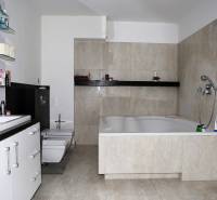 Ein Badezimmer mit einer großen Badewanne und hellen Fliesen in einem Einfamilienhaus.