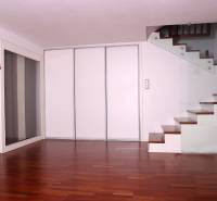 Innenraum eines Einfamilienhauses mit Holzboden und Treppe mit Glasgeländer.