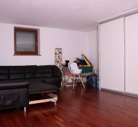 Ein Einfamilienhaus mit einem schwarzen Sofa, weißen Schränken und einem Boden mit Holzdekor.