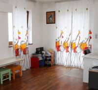 Kinderzimmer in einem Einfamilienhaus mit bunten Vorhängen und einem Boden in Holzoptik.