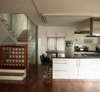 Küche in einem Einfamilienhaus mit Holzboden und Glasgeländer an der Treppe.