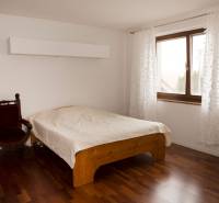 Schlafzimmer in einem Einfamilienhaus mit Bett, Sessel und Boden in Holzoptik.