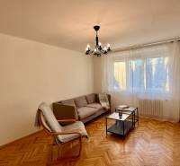 Wohnzimmer mit Sofa, Sessel, Kronleuchter und Holzboden in einer 3-Zimmer-Wohnung.