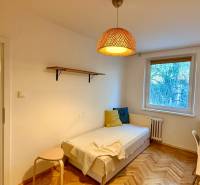 Ein Zimmer in einer 3-Zimmer-Wohnung mit einem Bett, einem Tisch und einem Boden in Holzoptik.