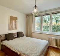 Schlafzimmer mit Holzboden, Bett und großem Fenster in einer 3-Zimmer-Wohnung.