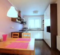 Küche in einer 2-Zimmer-Wohnung mit Holzboden und rosa Accessoires.