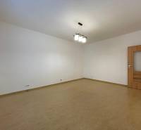 Ein geräumiges Zimmer in einer 2-Zimmer-Wohnung mit einem Boden in Holzoptik und weißen Wänden.