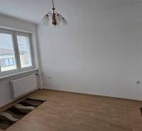 Ein Zimmer mit großen Fenstern, einem Boden in Holzoptik und einem Kronleuchter in einer 3-Zimmer-Wohnung.