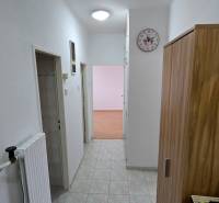 Flur in einer 3-Zimmer-Wohnung mit Fliesen, weißen Wänden und Holzmöbeln.