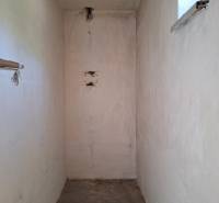 Ein enger Innenraum in einem Einfamilienhaus mit einem kleinen Fenster und Betonboden.