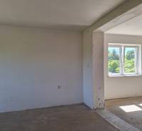 Ein unmöbliertes Zimmer in einem Einfamilienhaus mit Blick auf den Garten durch ein Kunststofffenster.