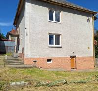 Ein Einfamilienhaus in Šíd mit einem steilen Dach und einem gepflegten Garten mit Rasen.