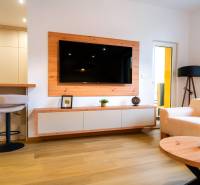 Wohnzimmer in einer 3-Zimmer-Wohnung mit Holzboden, Fernseher und cremefarbenen Sofas.