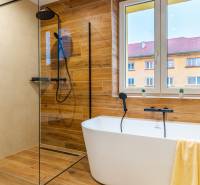 Badezimmer in einer 3-Zimmer-Wohnung mit Badewanne, Dusche und Boden in Holzoptik.