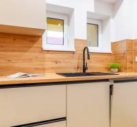 Küche in einer 3-Zimmer-Wohnung mit Holzelementen, Spüle und Schränken.