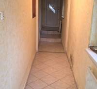 Ein schmaler Innenflur mit Fliesenboden und Holzdecke in einem Einfamilienhaus.