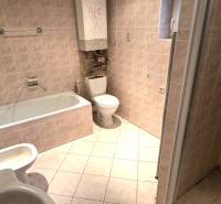 Badezimmer in einem Einfamilienhaus mit Badewanne, Waschbecken und WC. Fliesen in heller Farbe.