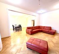 Wohnzimmer in einer Vierzimmerwohnung mit rotem Sofa und Holzboden.