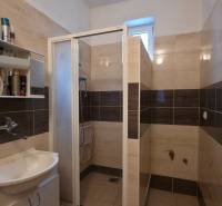 Ein Badezimmer mit Waschbecken und Dusche, in hellen Fliesentönen gehalten.